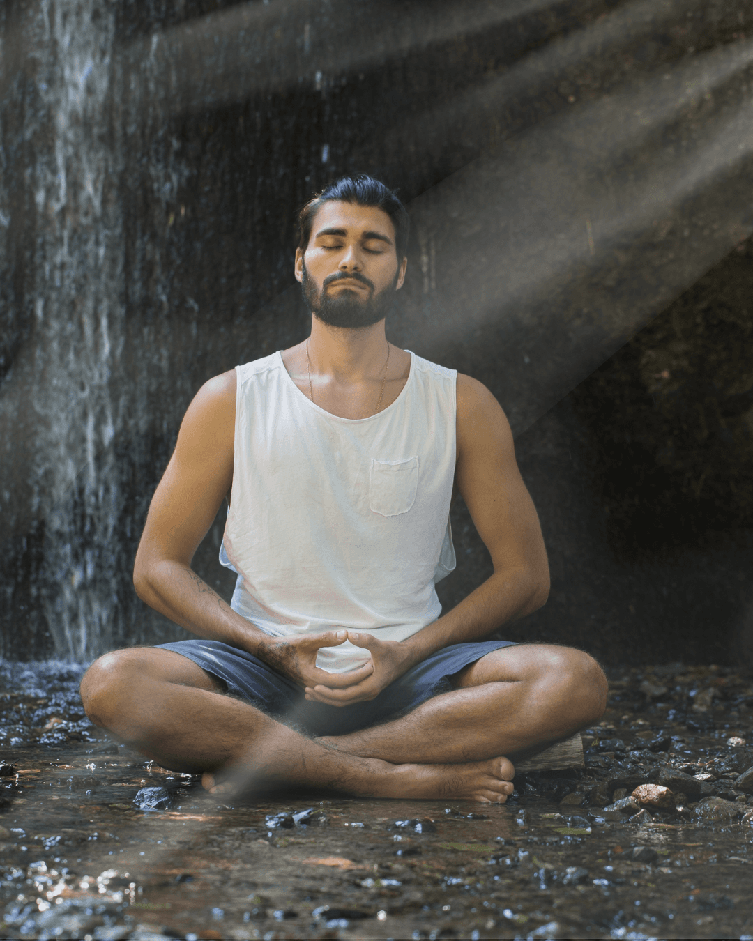 Man meditating by a waterfall